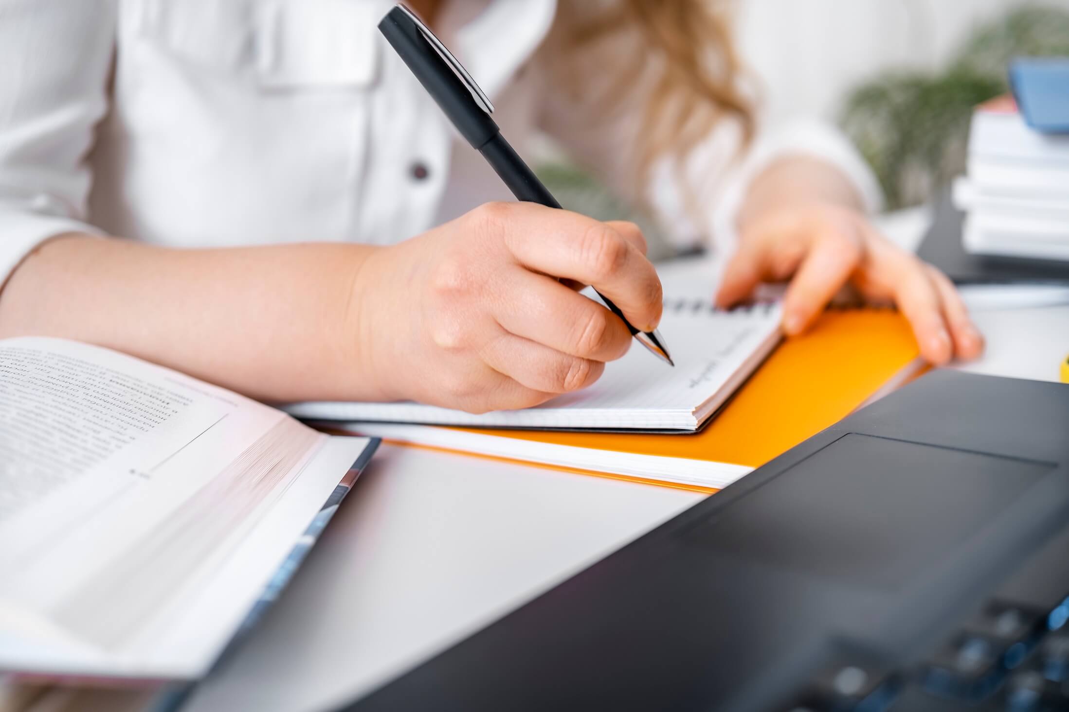 Close,Up,Of,Woman,Hand,Writing,Notes,In,Notebook,Near