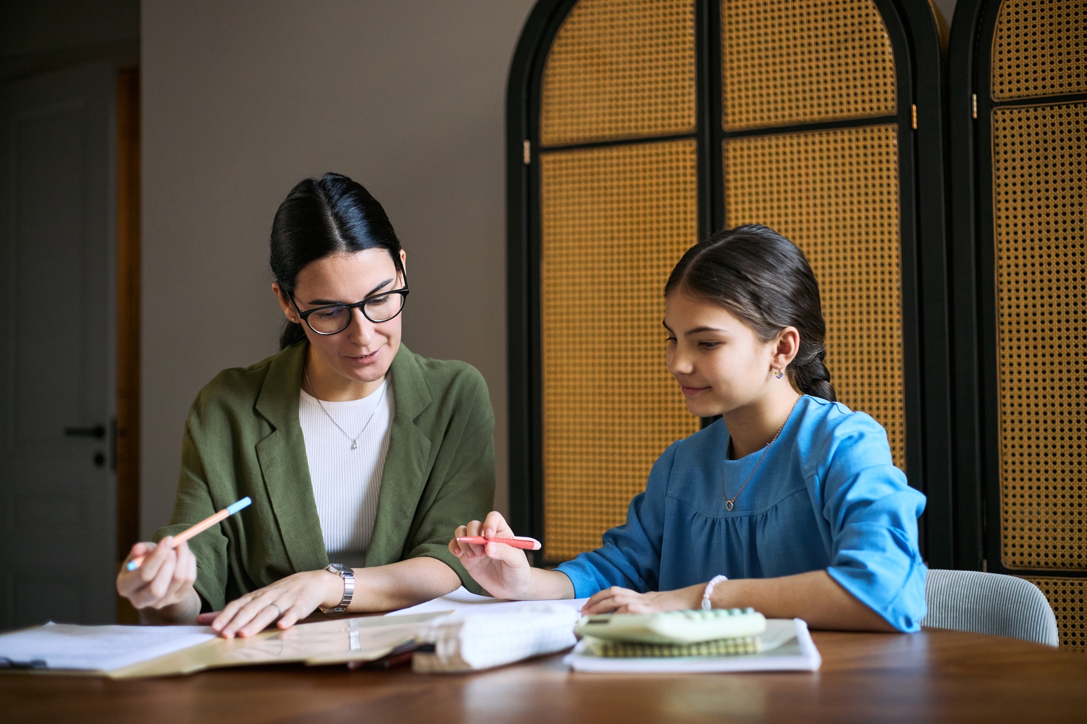 Young,Adult,Woman,Tutoring,Schoolgirl,,Reviewing,Workbook,And,Guiding,Homework
