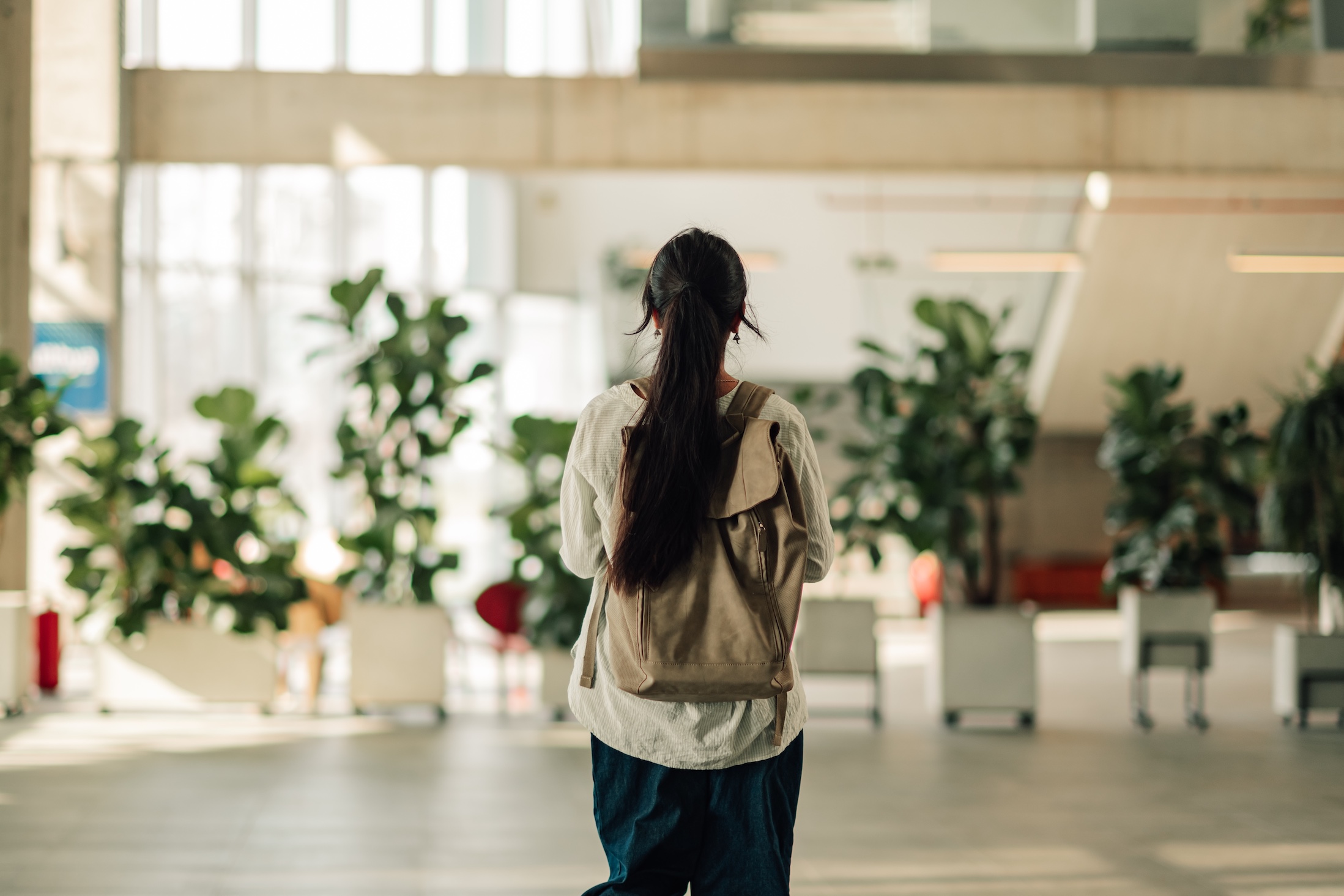 Young,Woman,Student,Walking,Through,A,Modern,University,Or,College