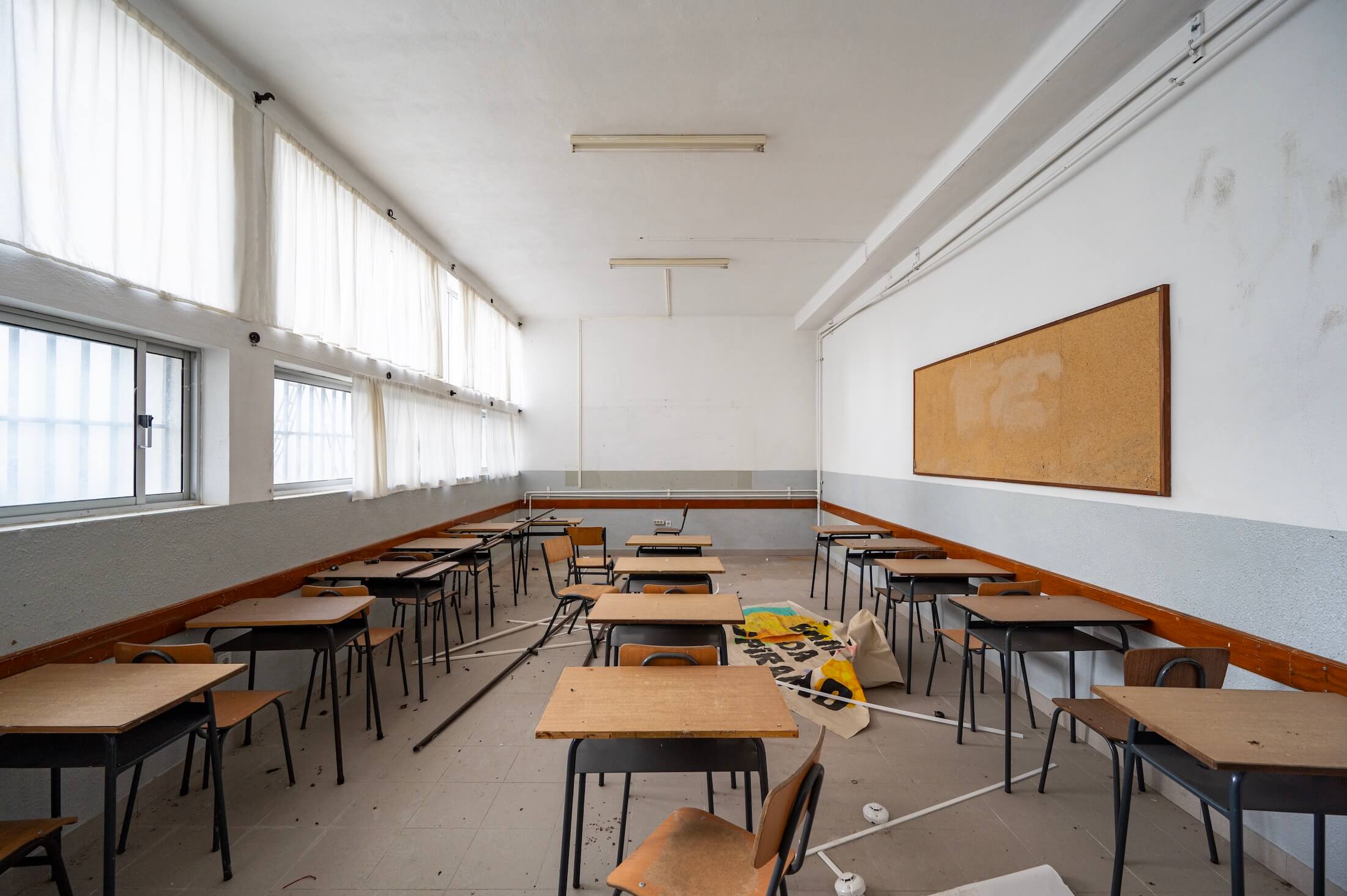Empty,Abandoned,Classroom,With,Scattered,Desks,And,Natural,Light,,Symbolizing
